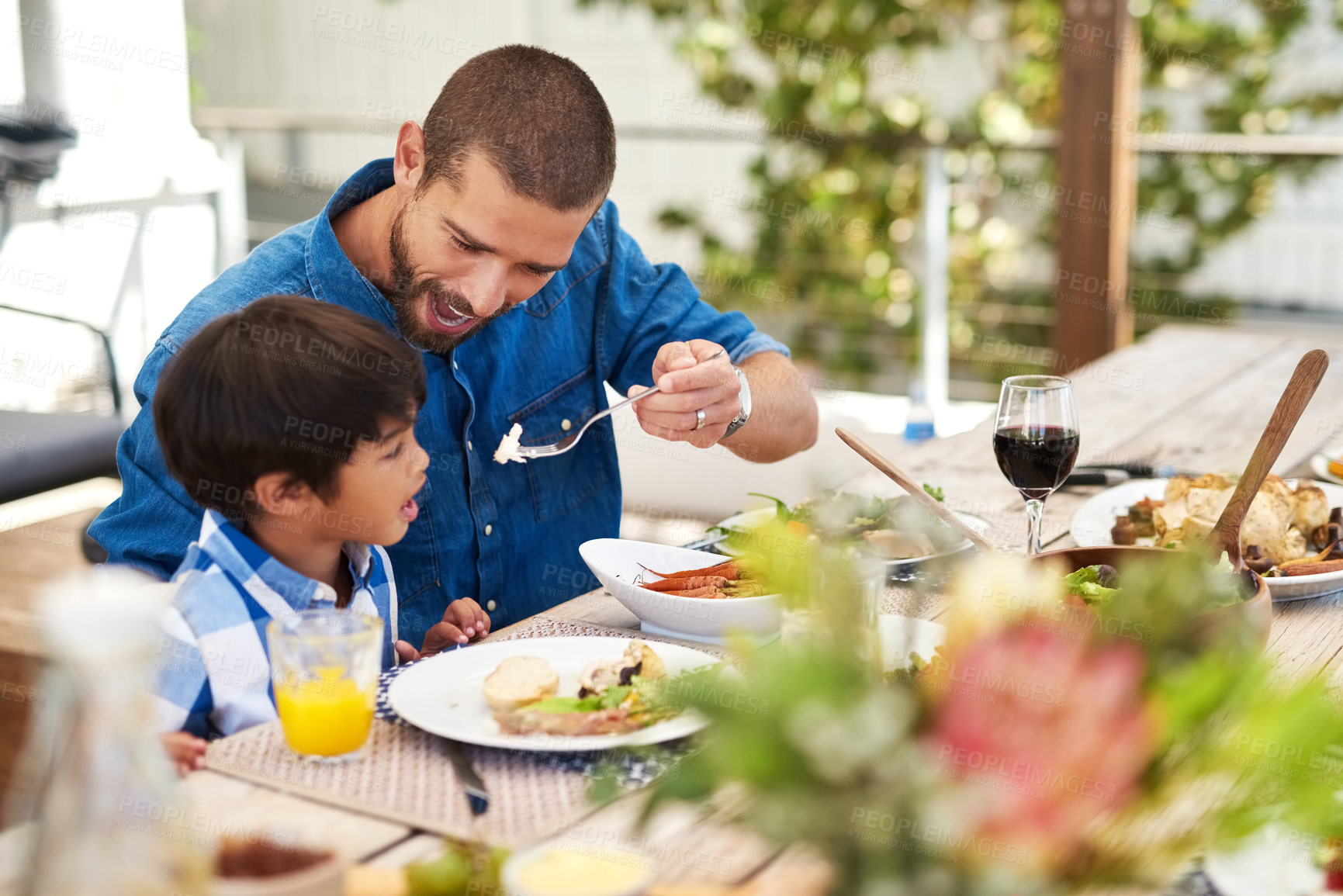 Buy stock photo Shot of a father feeding his young son while having a meal together outdoors