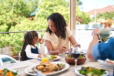 Buy stock photo Shot of an adorable little girl and her mother enjoying themselves during a meal with family outdoors