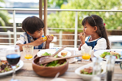 Buy stock photo Shot of two adorable little children enjoying a meal together outdoors