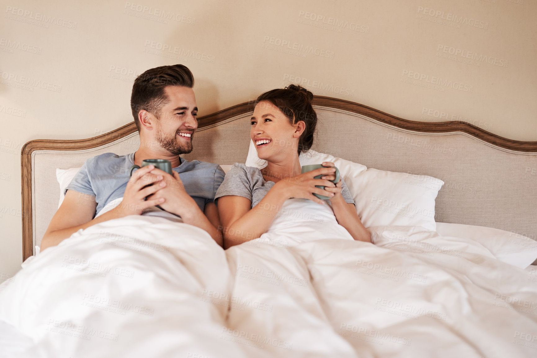 Buy stock photo Shot of a happy young couple drinking coffee in bed in their bedroom at home