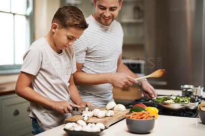 Buy stock photo Cropped shot of a young boy helping his father cook in the kitchen