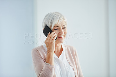 Buy stock photo Cropped shot of a happy senior woman taking a phonecall while standing indoors in a retirement home
