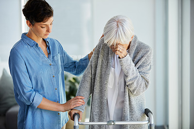 Buy stock photo Cropped shot of an affectionate young woman consoling her upset aged mother while assisting her to use a walker