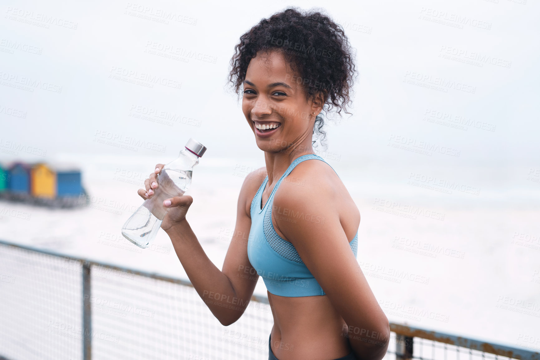 Buy stock photo Portrait of a sporty young woman drinking water while exercising outdoors