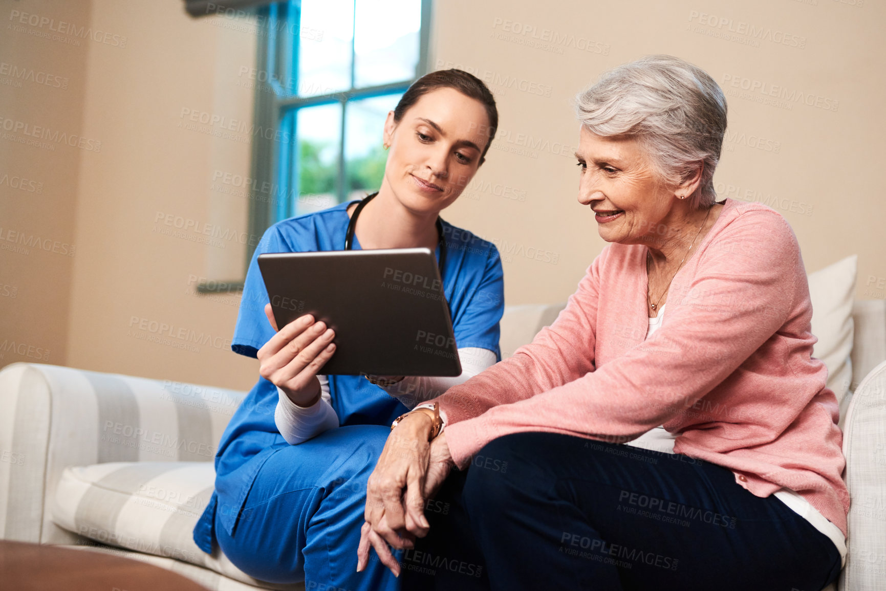 Buy stock photo Shot of a female nurse showing her senior patient something on a digital tablet