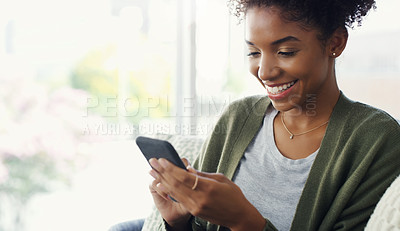 Buy stock photo Cropped shot of an attractive young woman using her cellphone while sitting in the living room during the day