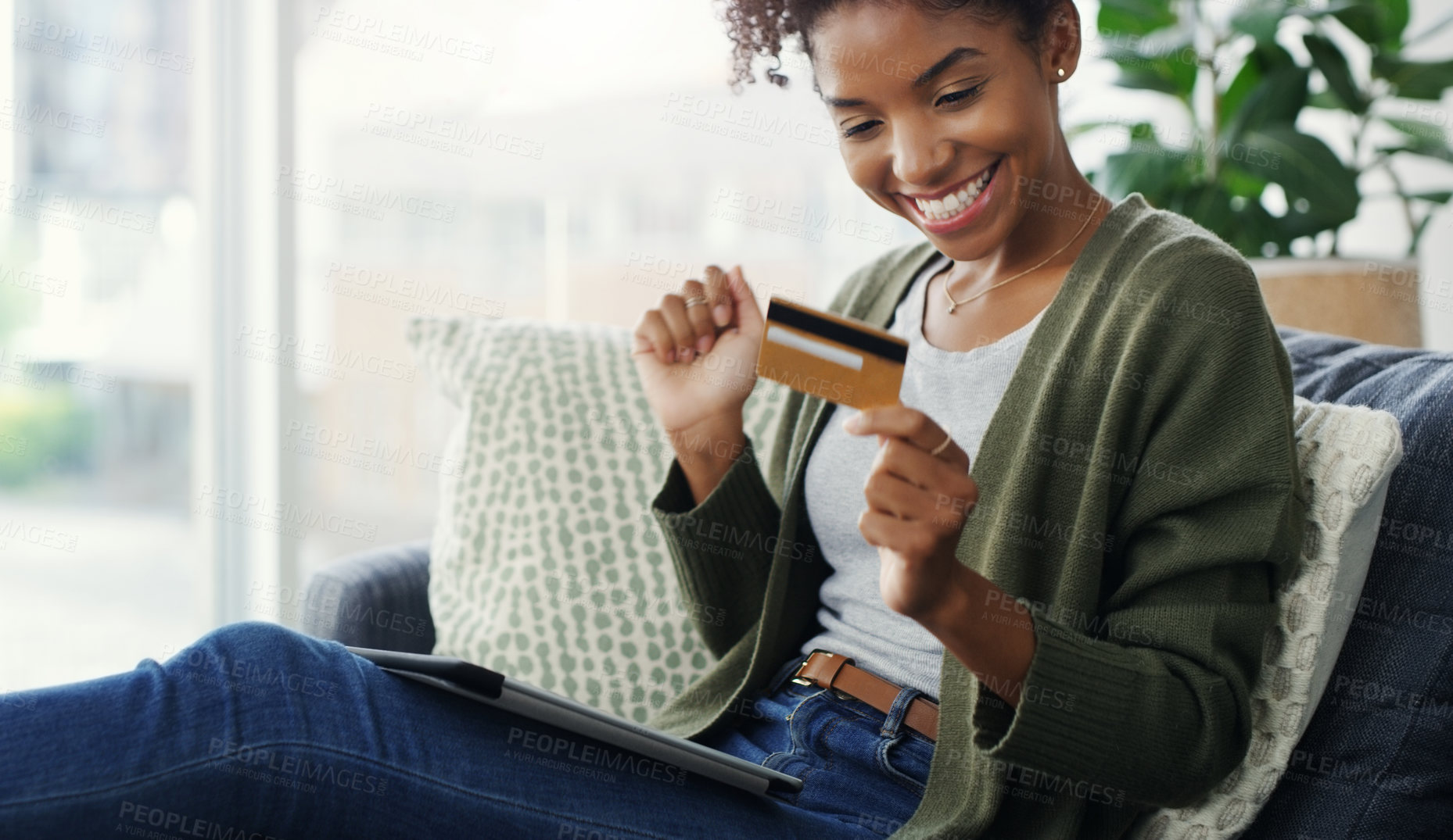 Buy stock photo Cropped shot of an attractive young woman using a tablet for online shopping while sitting on the sofa