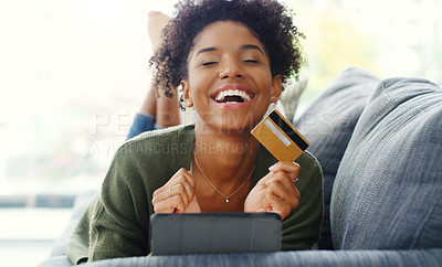 Buy stock photo Cropped shot of an attractive young woman using a tablet for online shopping while lying down on the sofa