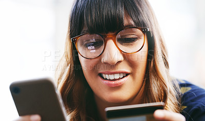 Buy stock photo Shot of a young woman using a credit card and smartphone
