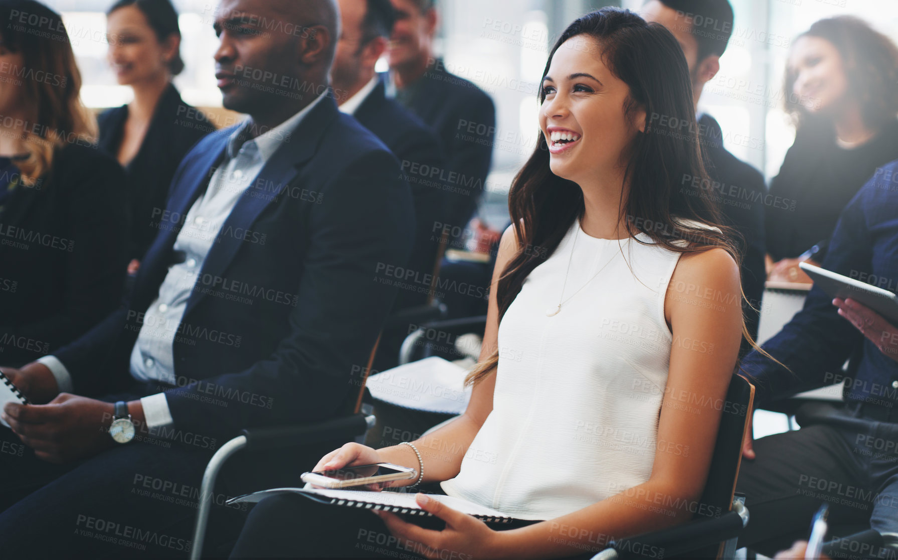 Buy stock photo Shot of a happy young businesswoman sitting in the audience of a business conference