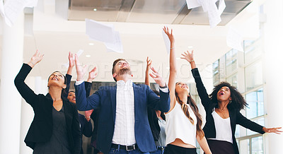 Buy stock photo Shot of a group of happy businesspeople tossing their paperwork in the air in a modern office