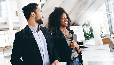 Buy stock photo Shot of a young businessman and businesswoman having a conversation while walking through a modern office