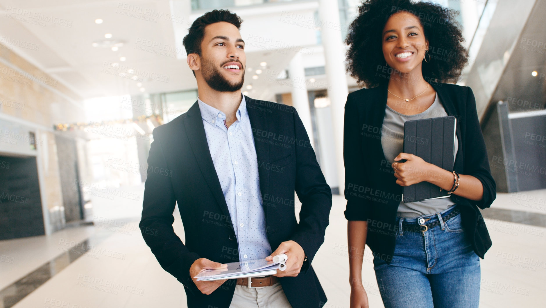 Buy stock photo Shot of a young businessman and businesswoman having a conversation while walking through a modern office