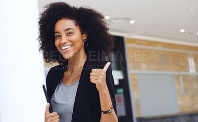 Buy stock photo Portrait of a confident young businesswoman showing a thumbs up gesture in a modern office