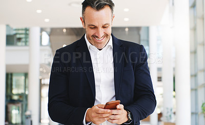 Buy stock photo Shot of a mature businessman using a smartphone while walking through a modern office