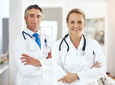 Buy stock photo Cropped portrait of two doctors standing with their arms crossed in the hospital corridor