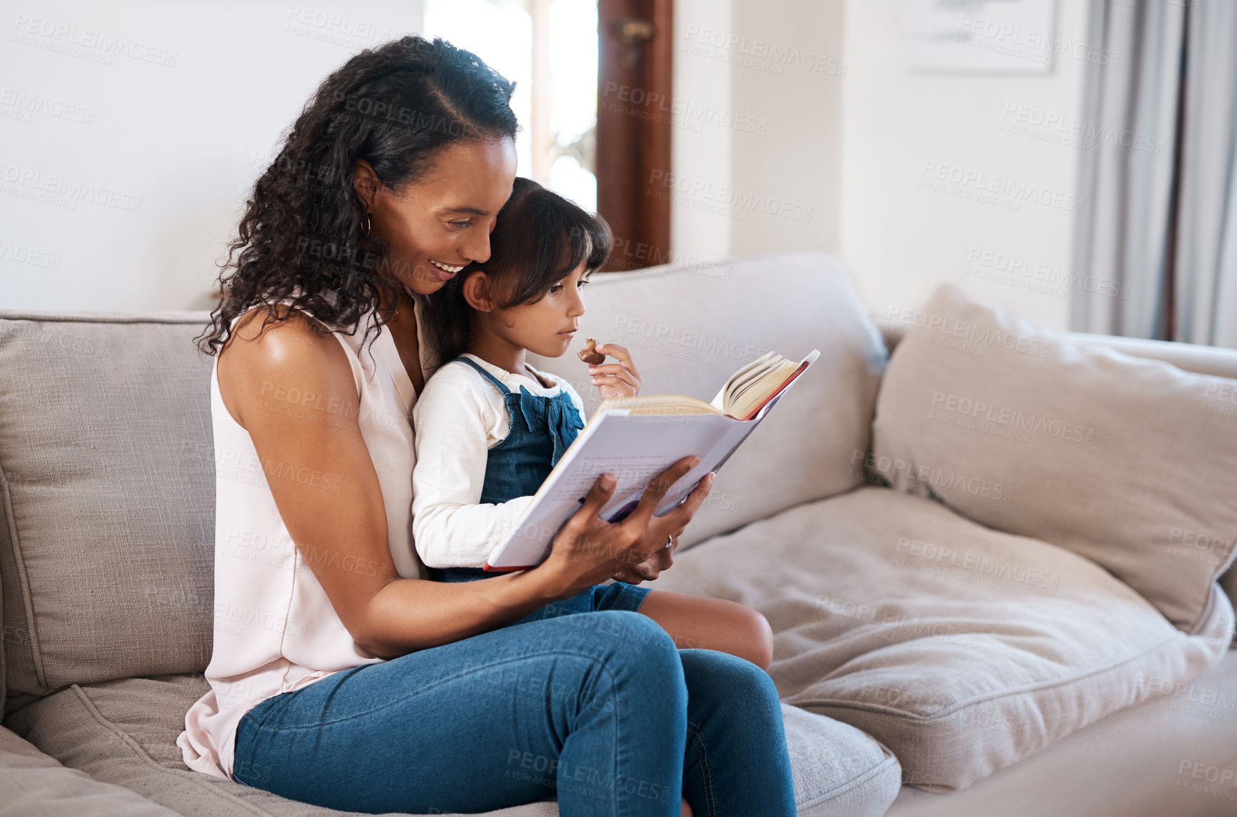 Buy stock photo Shot of a young girl reading a book while sitting with her mother at home