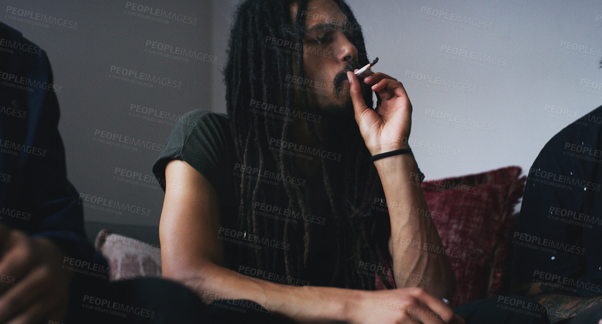 Buy stock photo Shot of two young men smoking a marijuana joint at home