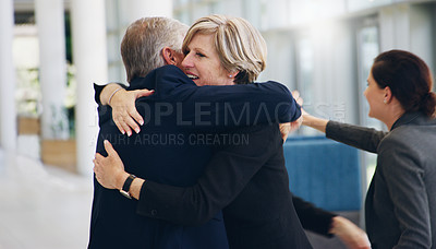 Buy stock photo Cropped shot of two mature businesspeople hugging each other while in the office during the day