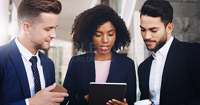 Buy stock photo Cropped shot of three businesspeople standing and working on a tablet while in the office during the day
