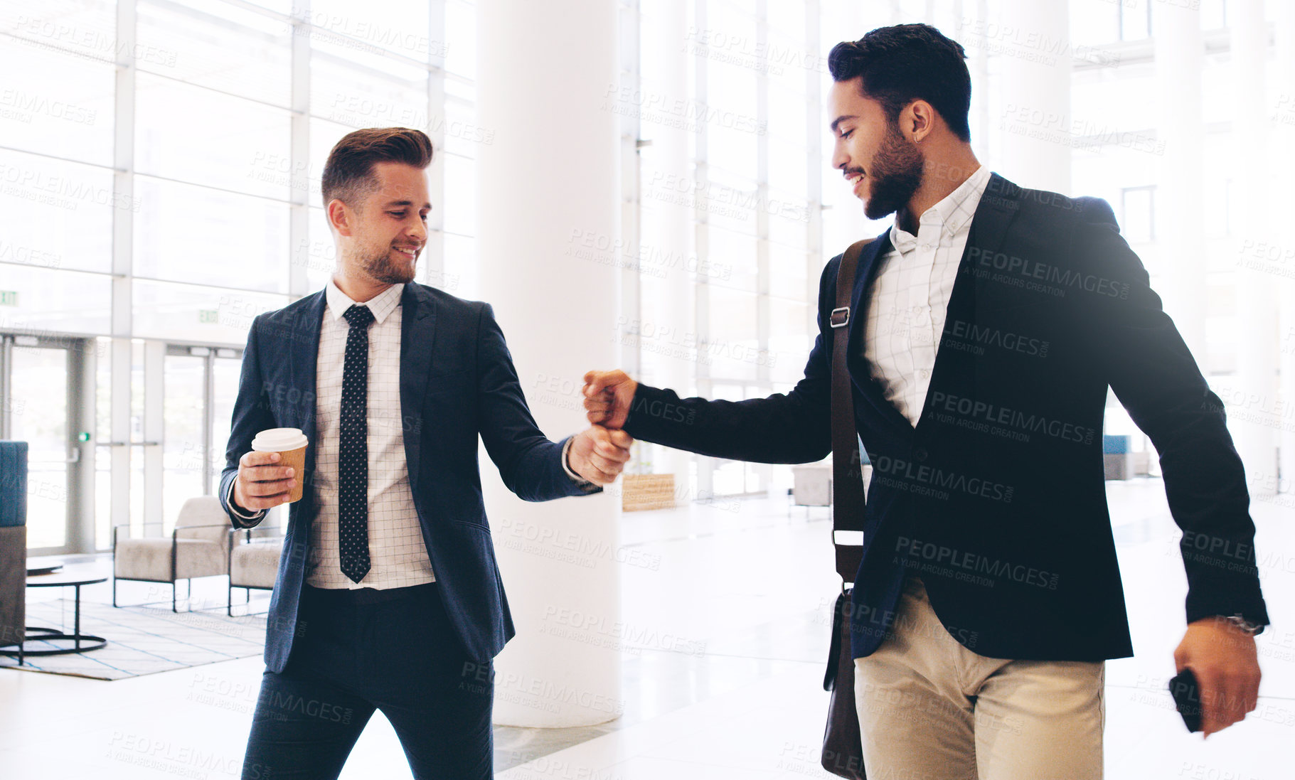 Buy stock photo Cropped shot of two handsome young businessmen greeting each other while in the office during the day