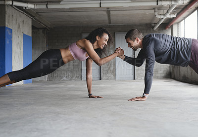 Buy stock photo Shot of a sporty young couple holding hands while exercising together inside an underground parking lot