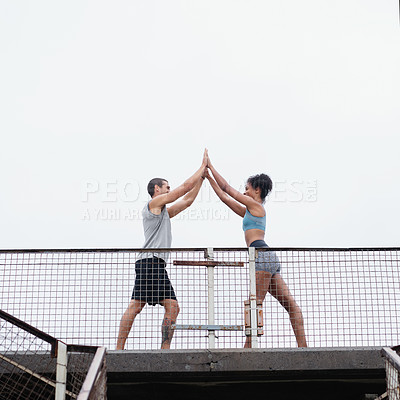 Buy stock photo Full length shot of a sporty young couple joining for a high five while exercising outdoors