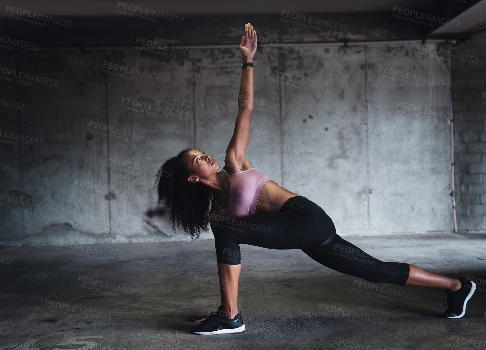 Buy stock photo Full length shot of an attractive young sportswoman stretching while exercising inside an underground parking lot