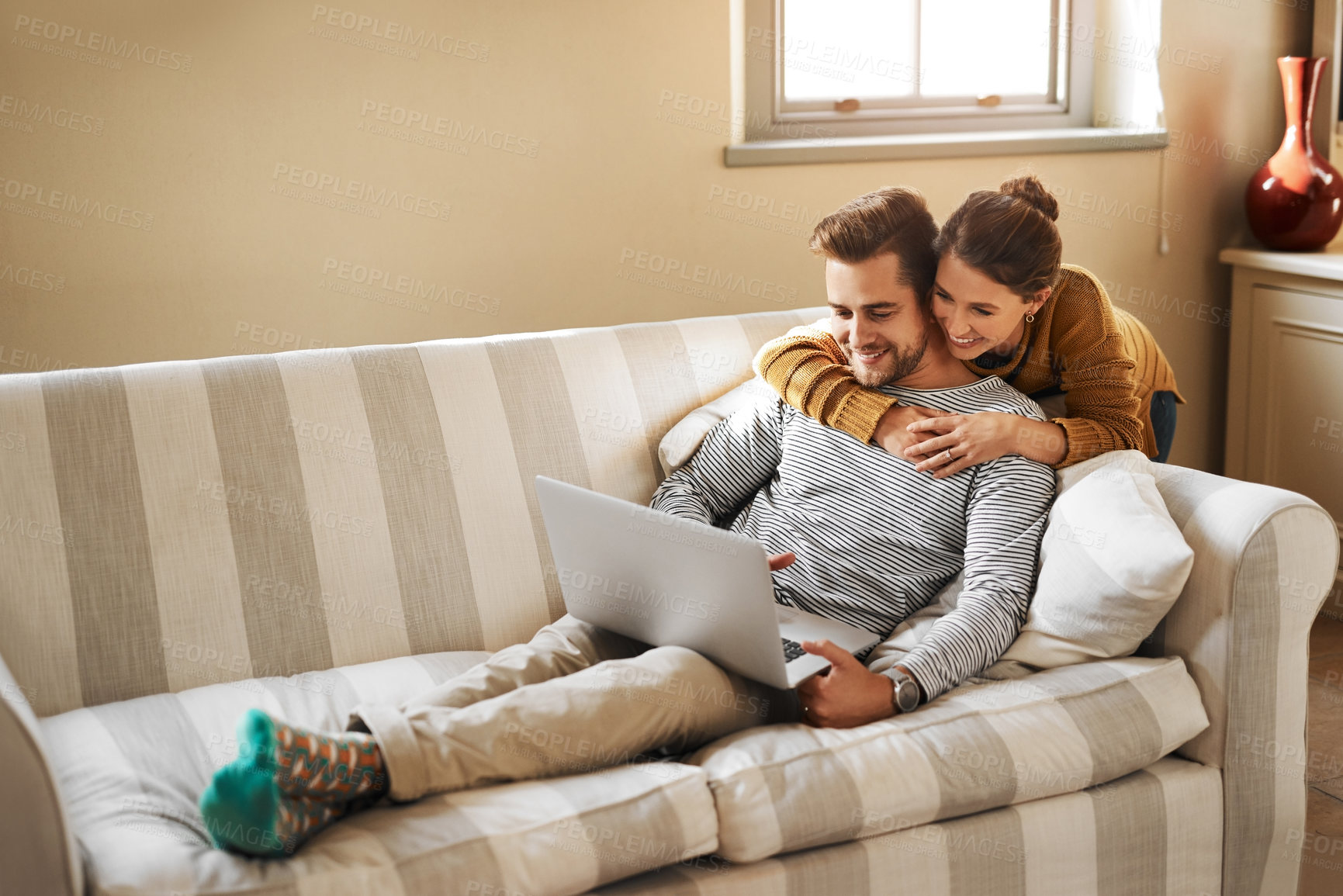 Buy stock photo Shot of a young couple using a laptop while relaxing at home