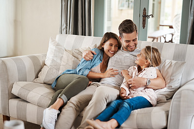 Buy stock photo Shot of an adorable little girl spending quality time with her parents on the sofa at home