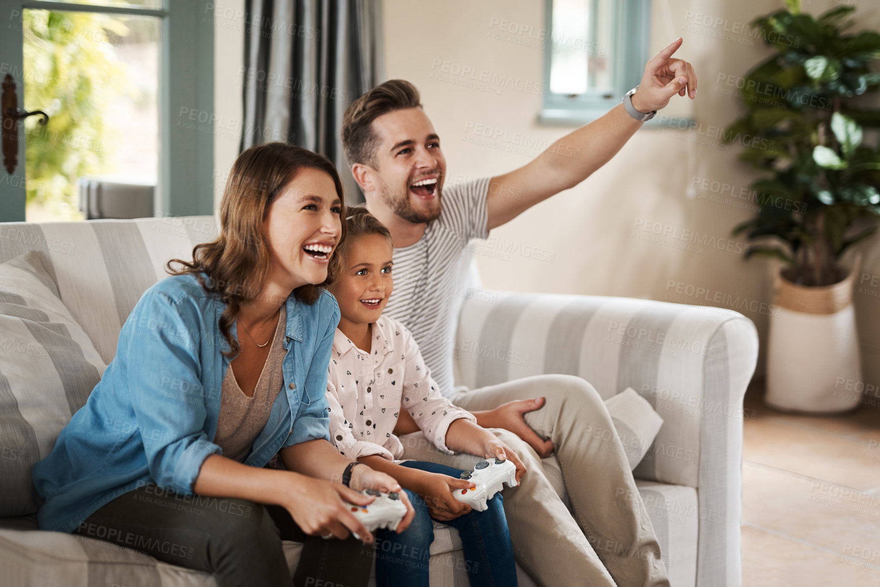 Buy stock photo Shot of a happy young family playing video games on the sofa at home