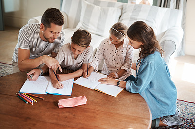 Buy stock photo Shot of a happy young family of four doing homework together
