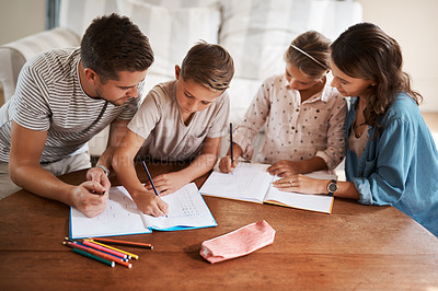 Buy stock photo Shot of a happy young family of four doing homework together