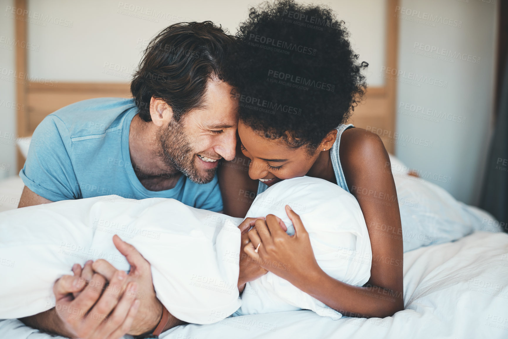 Buy stock photo Happy interracial couple, bed and laughing in relax for intimate morning, bonding or relationship at home. Man and woman smiling with laugh in joyful happiness or relaxing weekend together in bedroom