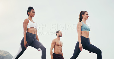 Buy stock photo Cropped shot of a group of young people standing and doing yoga while on the beach during an overcast day