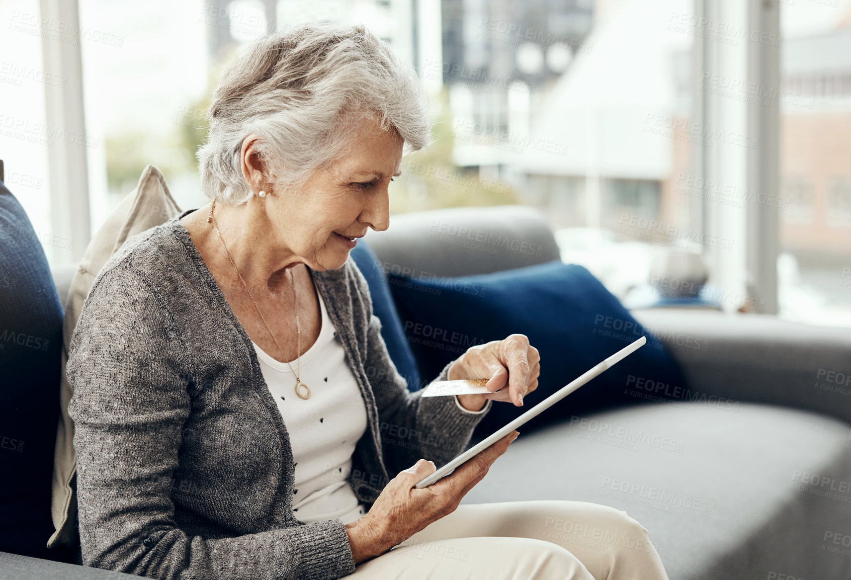 Buy stock photo Shot of a senior woman holding her credit card while browsing on a digital tablet
