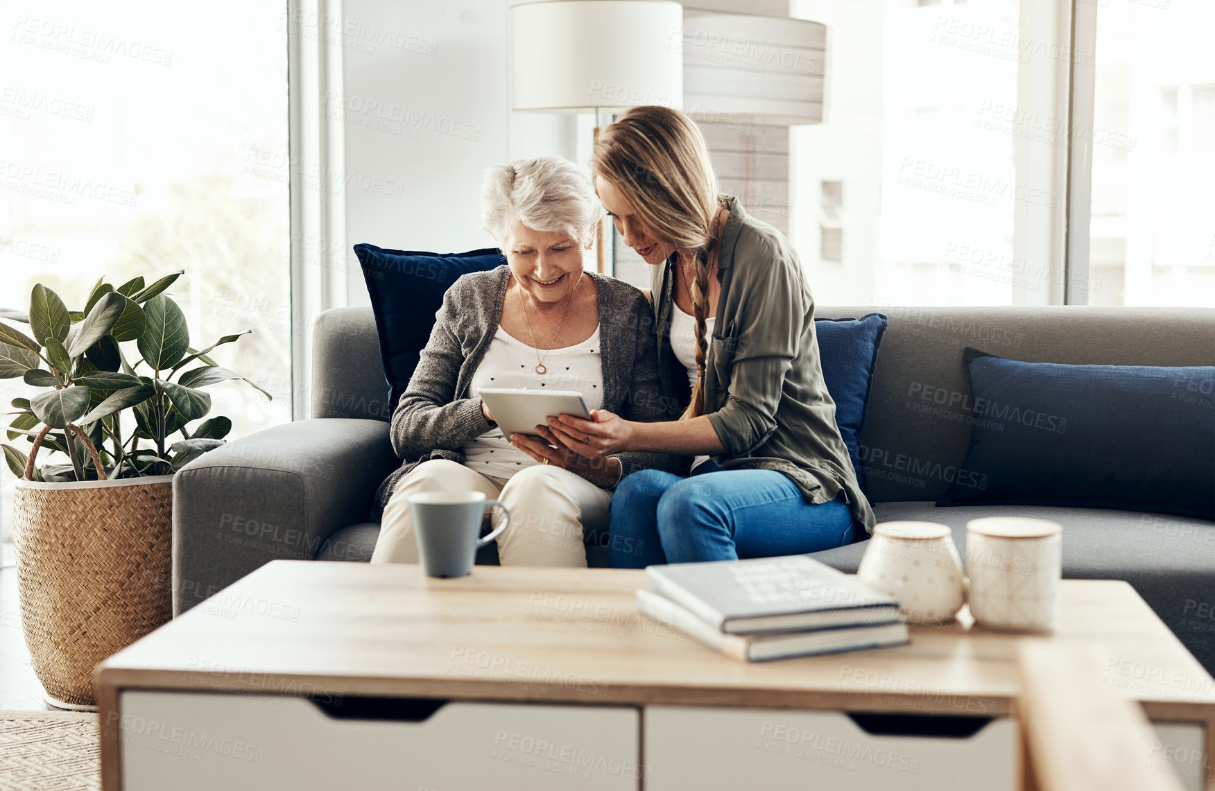 Buy stock photo Shot of a senior woman and her daughter using a digital tablet together