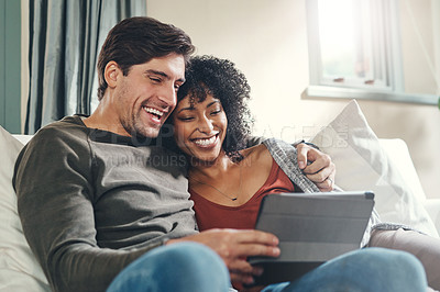 Buy stock photo Shot of an affectionate young couple using a digital tablet together while spending some quality time together at home