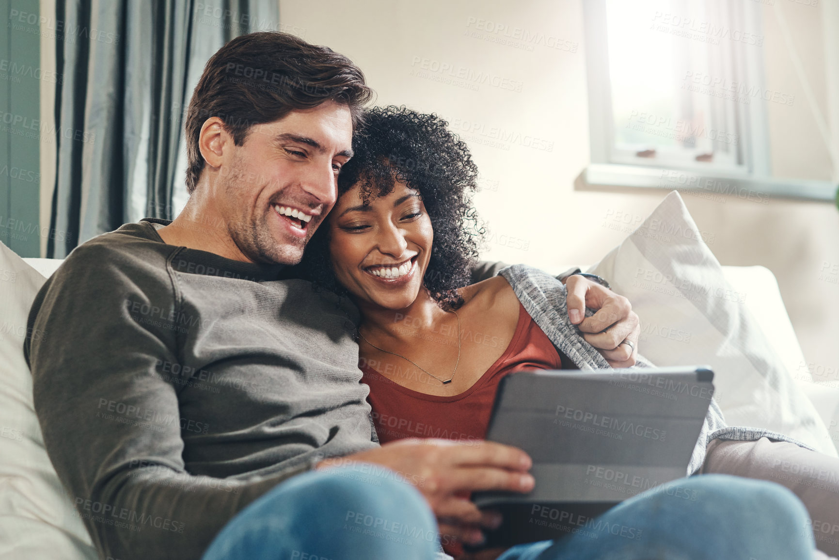 Buy stock photo Shot of an affectionate young couple using a digital tablet together while spending some quality time together at home