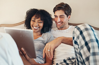Buy stock photo Shot of an affectionate young couple using a digital tablet while spending time together in bed at home