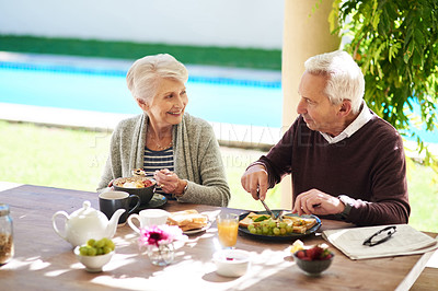 Buy stock photo Shot of an affectionate senior couple enjoying a meal together outdoors