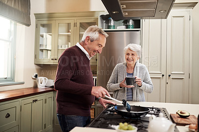 Buy stock photo Shot of an affectionate senior couple cooking together in their kitchen at home