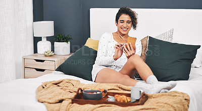 Buy stock photo Full length shot of an attractive young woman listening to music from her cellphone while having breakfast in bed