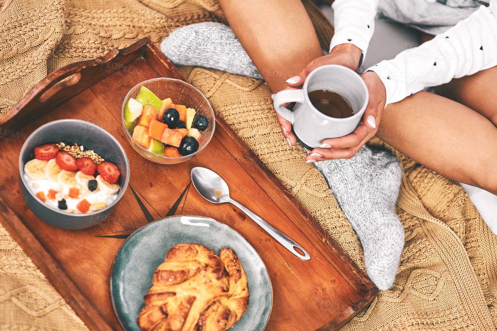 Buy stock photo Aerial shot of an unrecognizable woman holding a cup of coffee while sitting with an arranged breakfast tray in bed