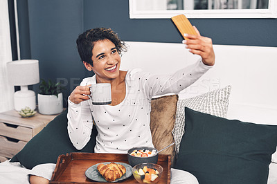 Buy stock photo Full length shot of an attractive young woman taking a selfie while posing with her breakfast tray in bed