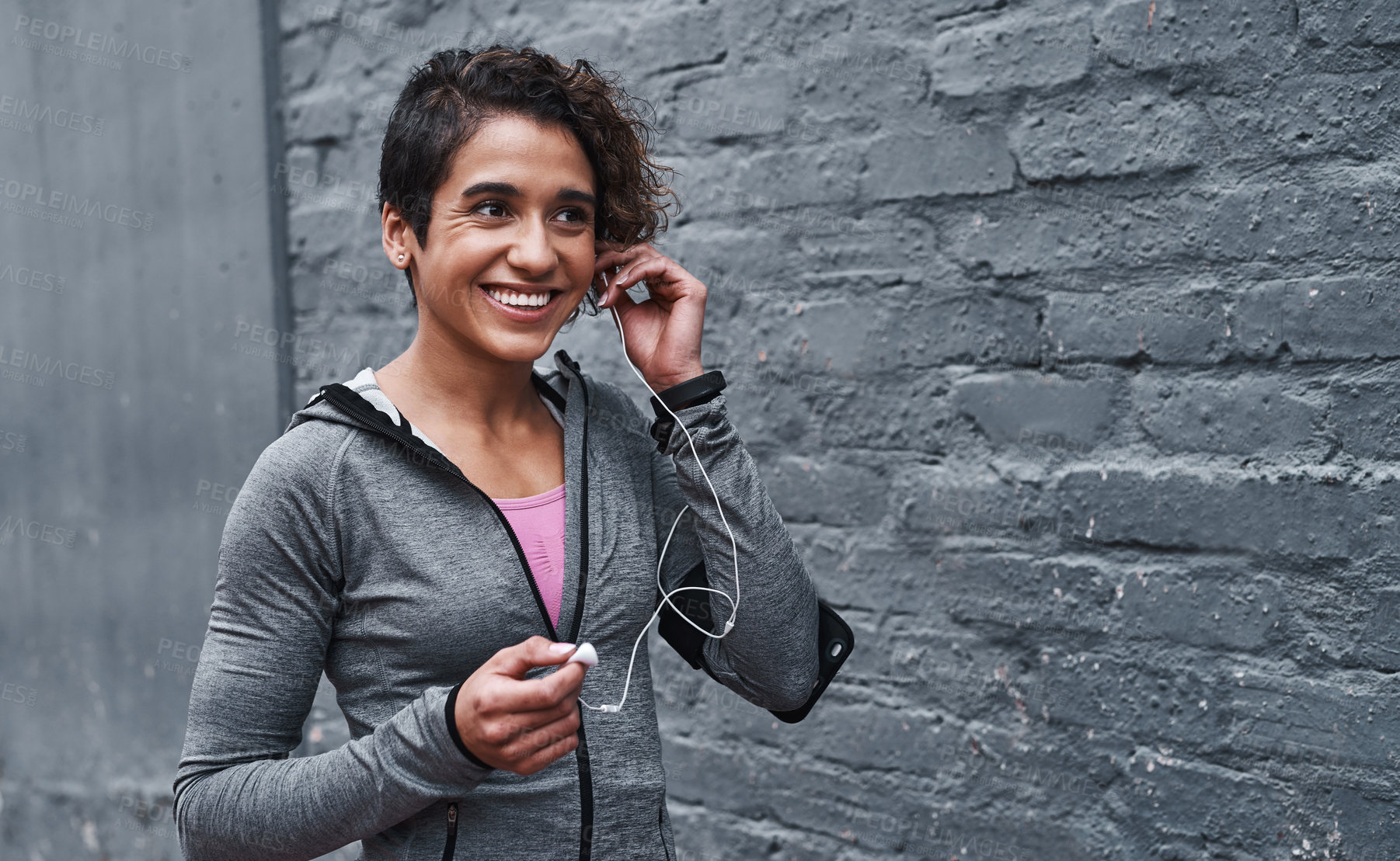 Buy stock photo Cropped shot of an attractive young woman standing and listening to music before going for a run outside