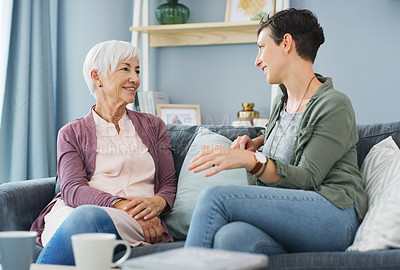 Buy stock photo Cropped shot of an attractive young woman sitting on the sofa and talking with her happy senior mother at home