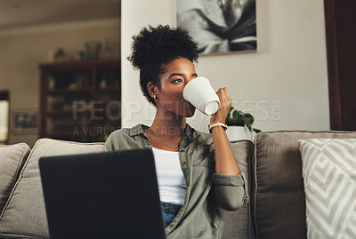 Buy stock photo Shot of a beautiful young woman drinking coffee and while working on her laptop at home