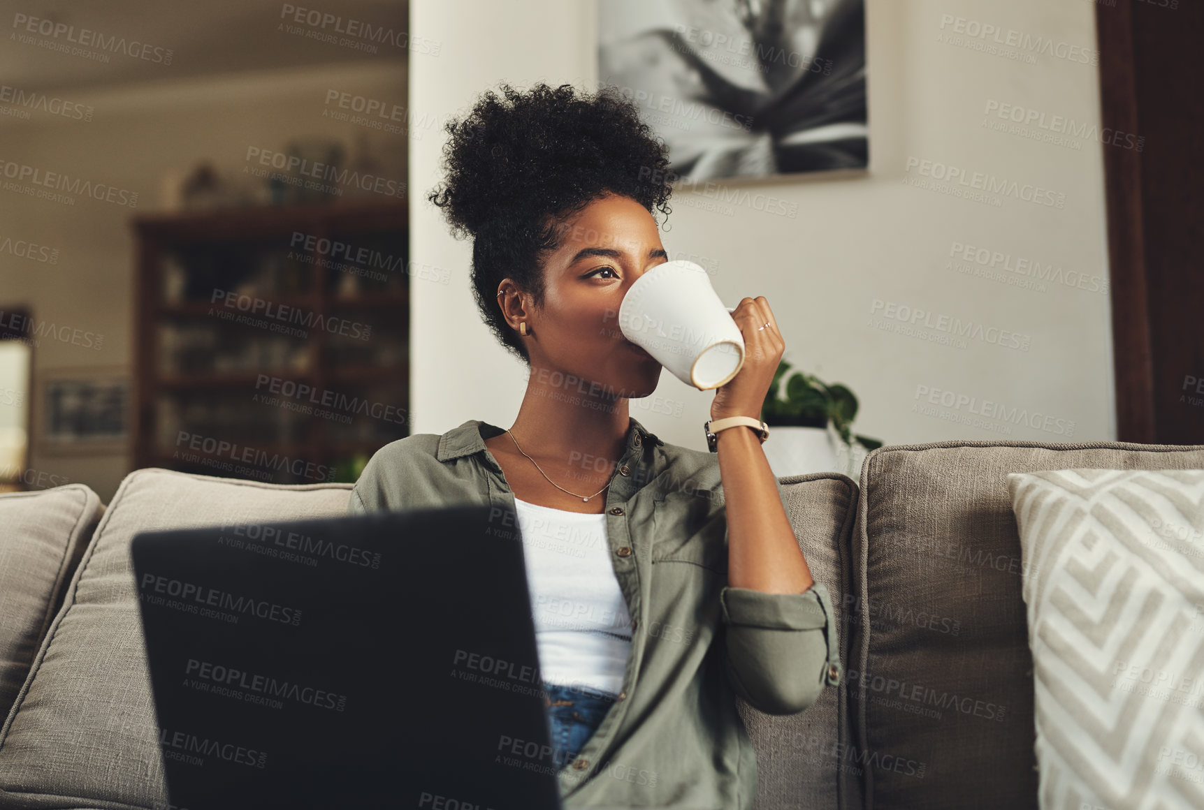 Buy stock photo Shot of a beautiful young woman drinking coffee and while working on her laptop at home