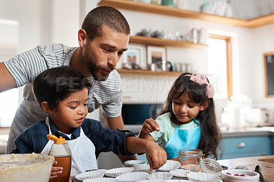 Buy stock photo Shot of a young man baking at home with his two young kids
